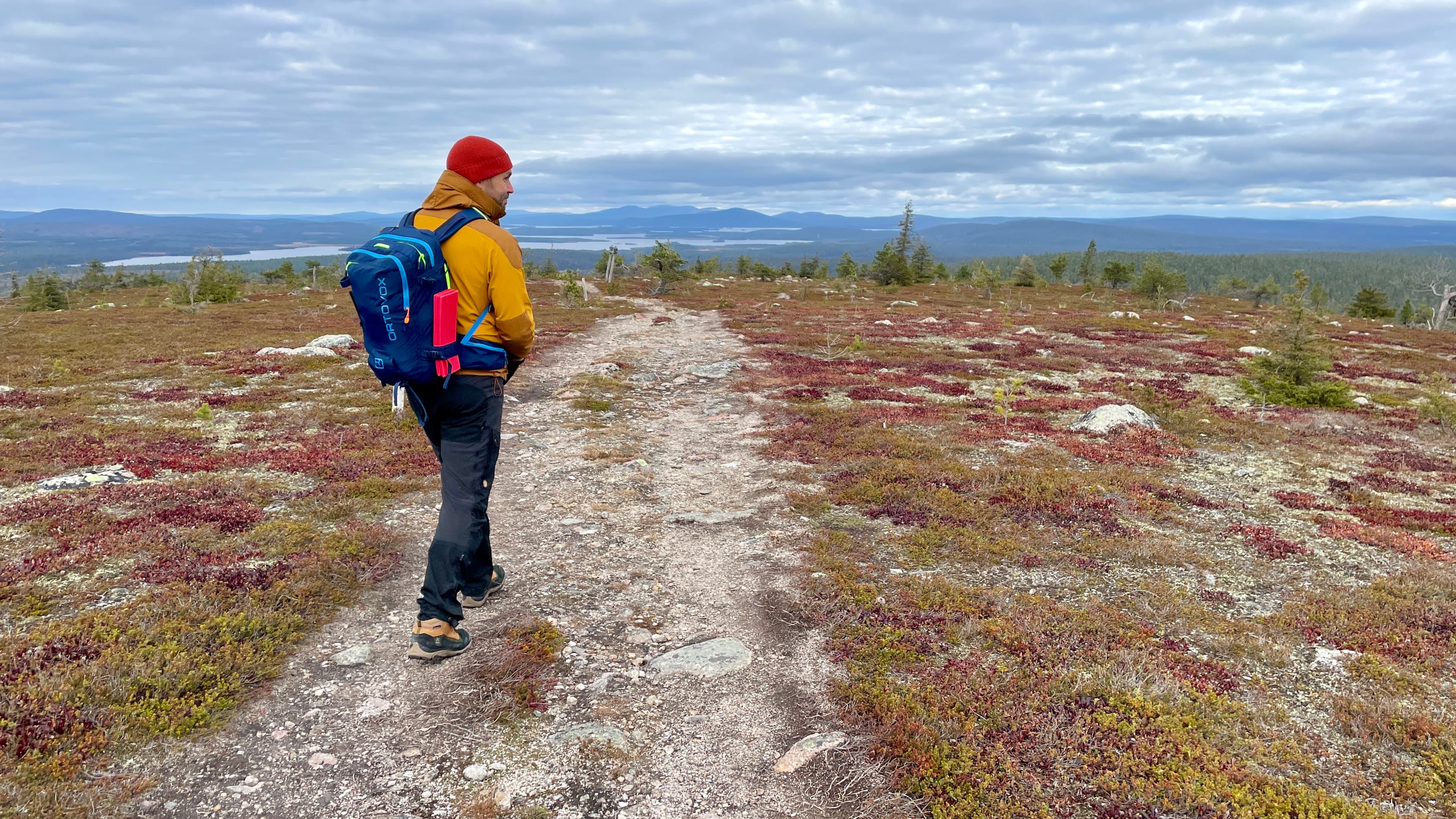 Artikkelissa kokemuksistaan kertova Tero vaeltaa kivikkoisella tunturipolulla. Taustalla avautuvat tunturit pilvisen taivaan alla.
